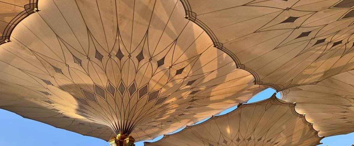 The retractable shade canopies over the courtyard of Masjid an-Nabawi in Madinah, lit by late afternoon sun.
