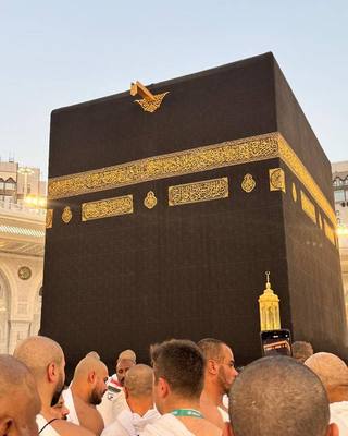 The Kaaba draped in the kiswah, seen from among pilgrims in ihram.