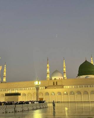 Masjid an-Nabawi at dusk with the green dome and floodlit minarets.