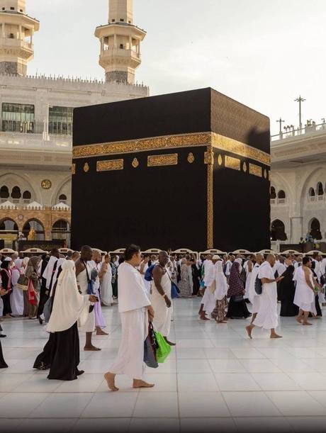 Pilgrims in ihram walking Tawaf around the Kaaba in the courtyard of Masjid al-Haram.
